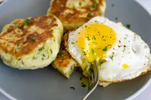 bubble and squeak cakes on a plate with a fried egg