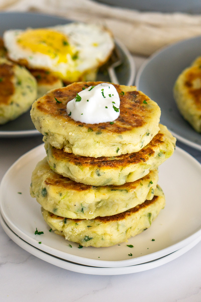 stack of bubble and squeak cakes on a plate with a dollop of sour cream