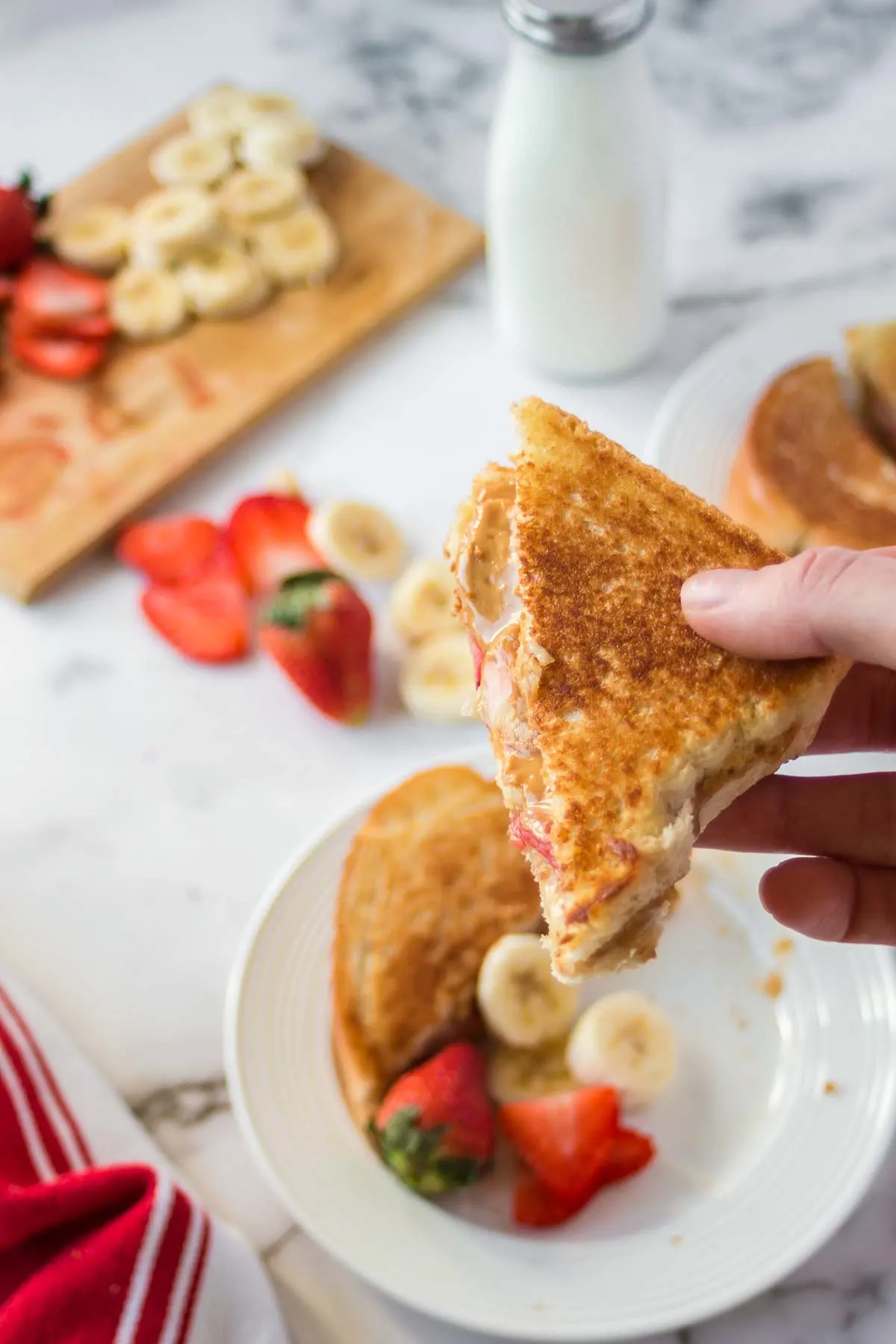 Hand holding grilled peanut butter banana sandwich.