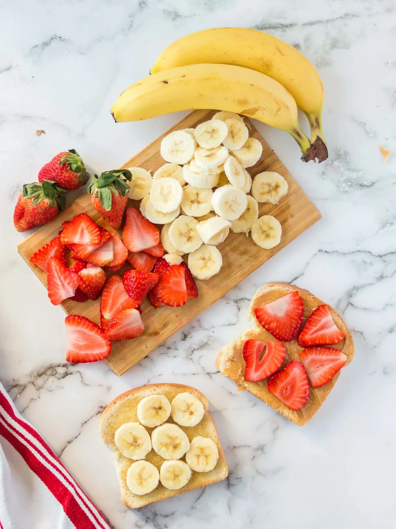 Peanut butter sandwich halves with banana slices and strawberry slices.