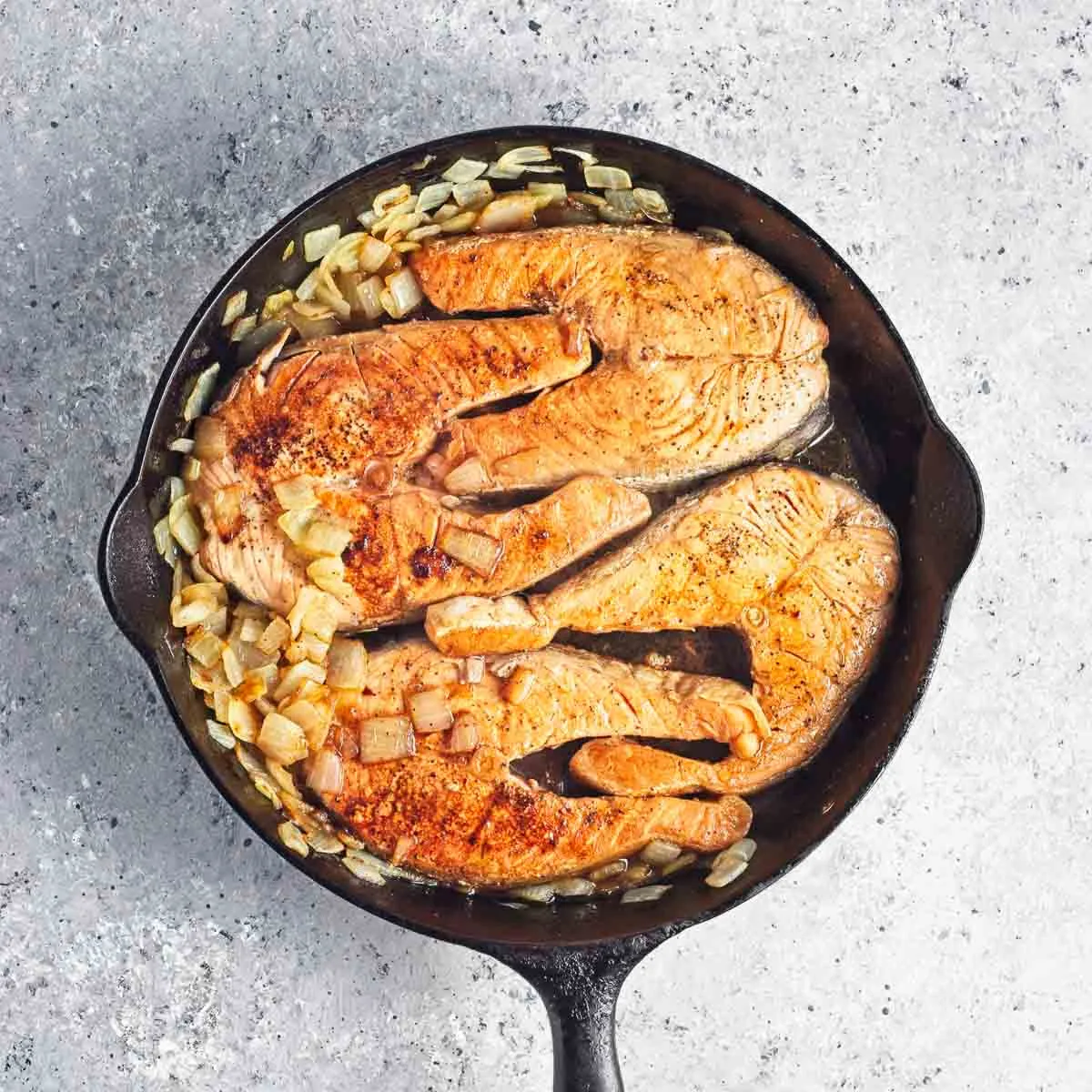 Seared salmon steaks in a cast iron pan.