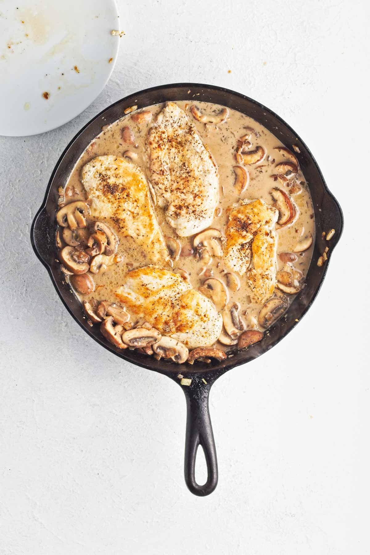 Browned chicken added to the pan with creamy mushroom sauce