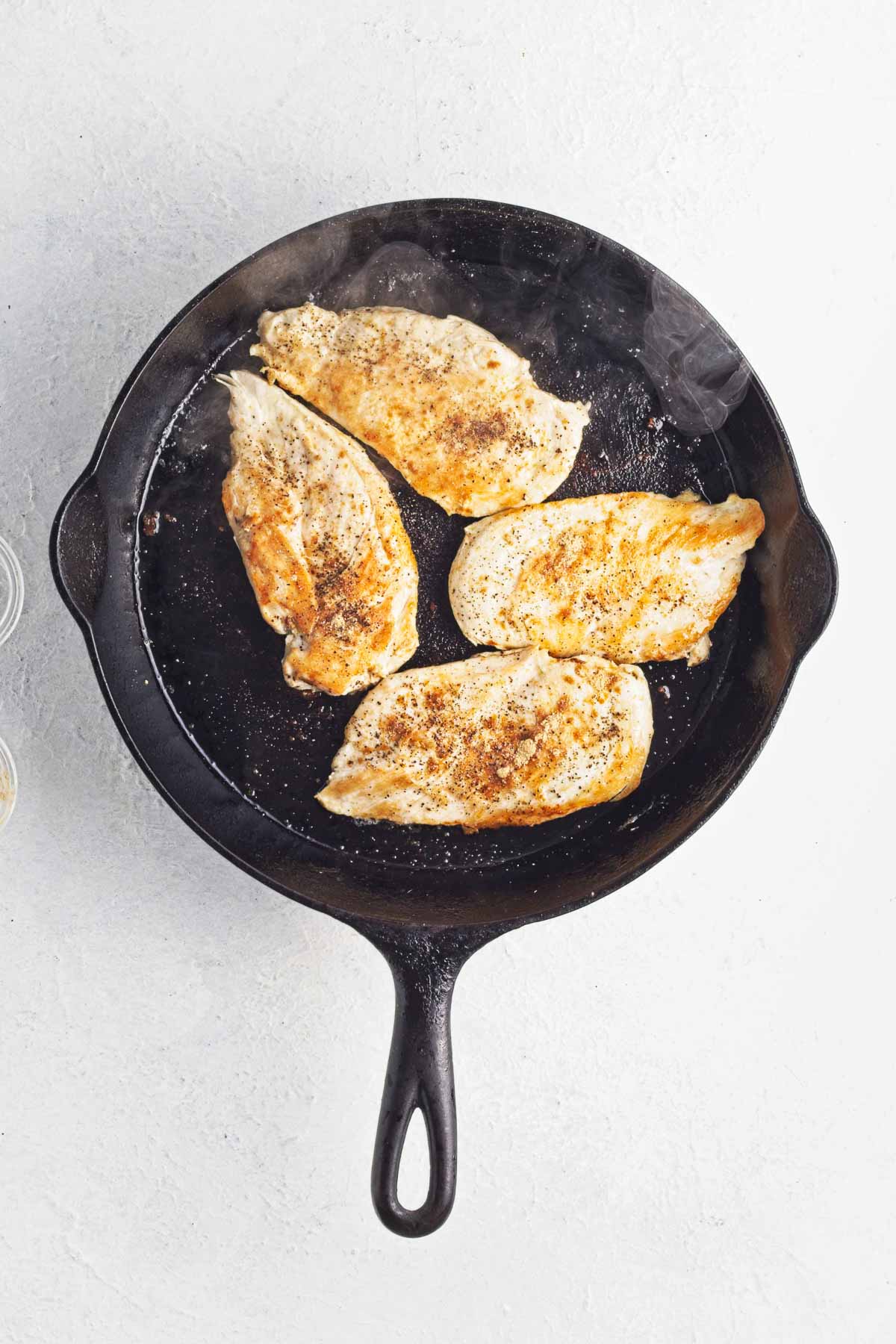 Browned thin-sliced chicken breasts in a skillet