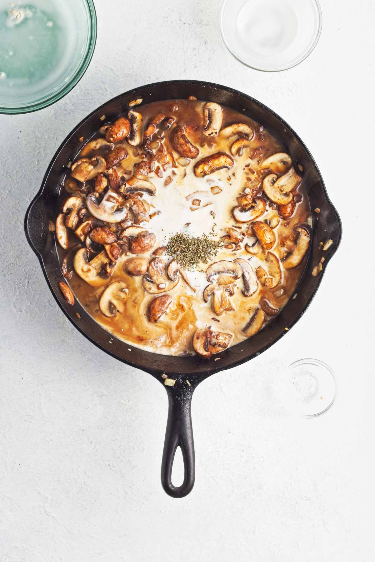 Skillet with half and half and broth added to sauteed mushrooms