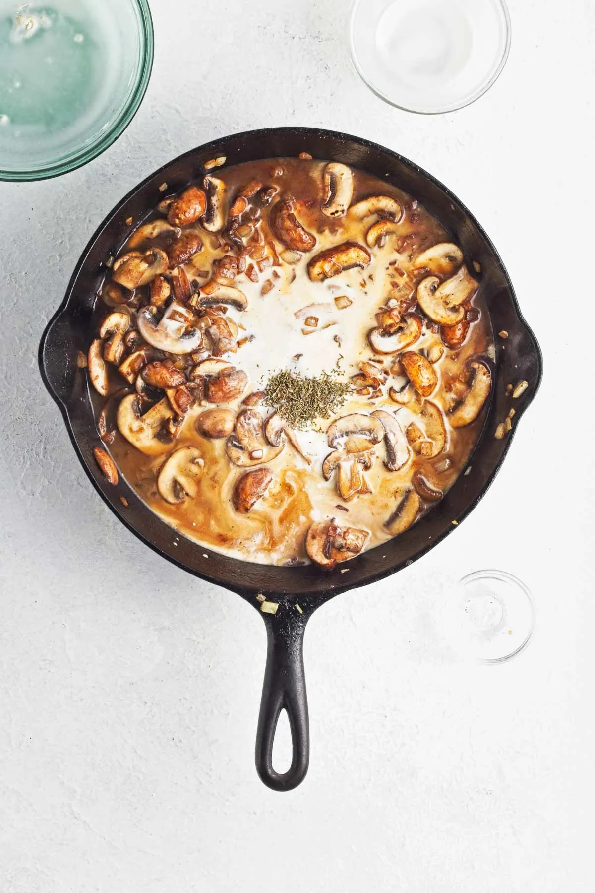 Skillet with half and half and broth added to sauteed mushrooms