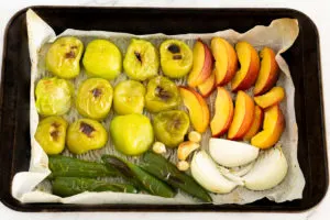 roasted tomatillos, peaches, jalapenos, and onions in a baking sheet