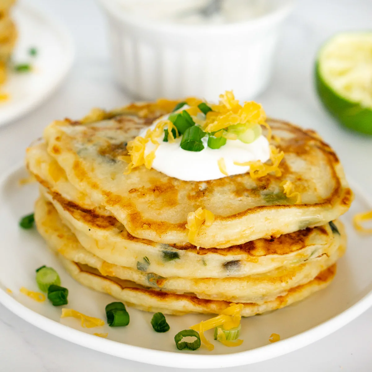 stack of savory cheesy pancakes with scallions on a plate