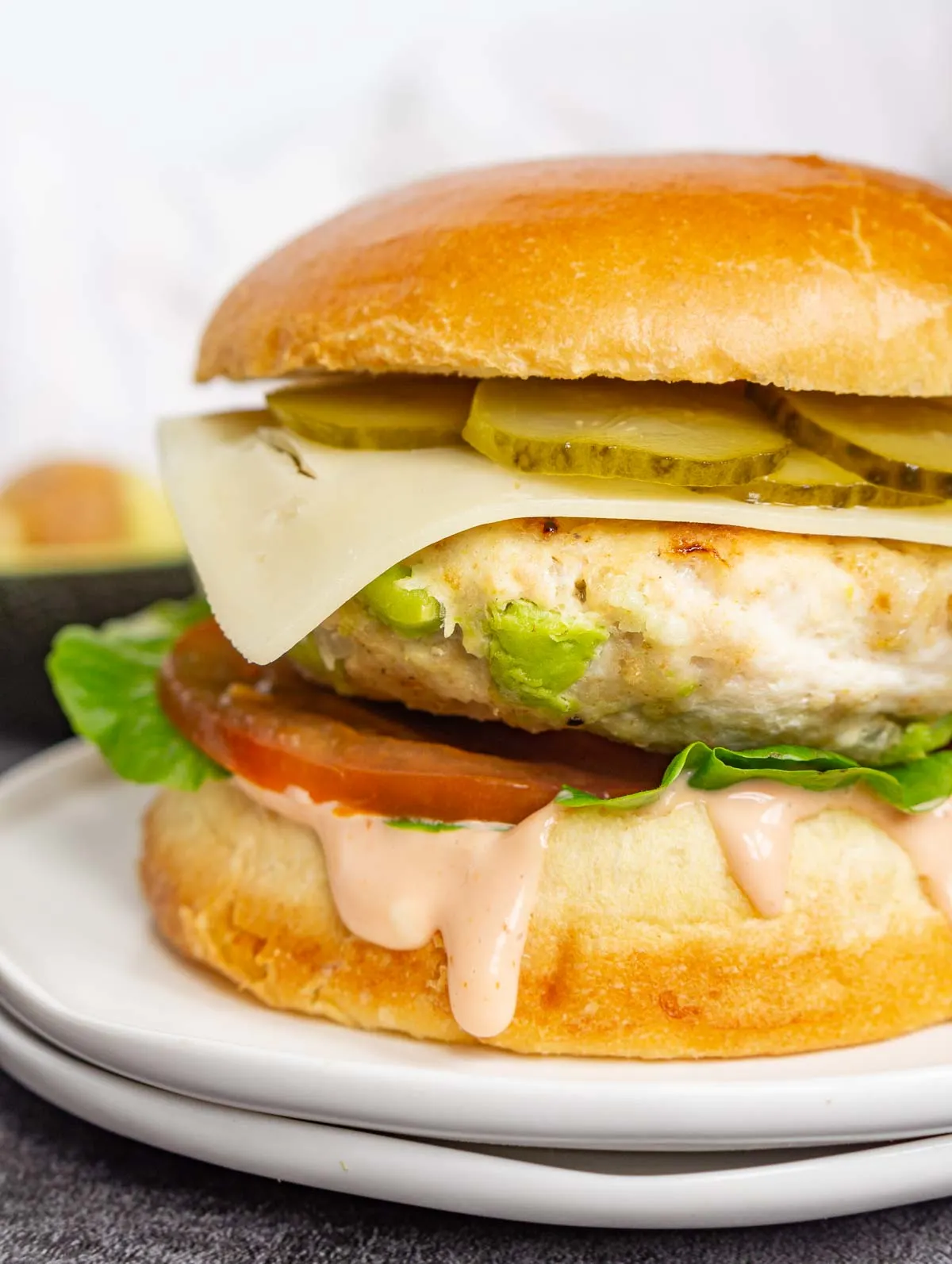 Close up of a chicken avocado burger with all the toppings.