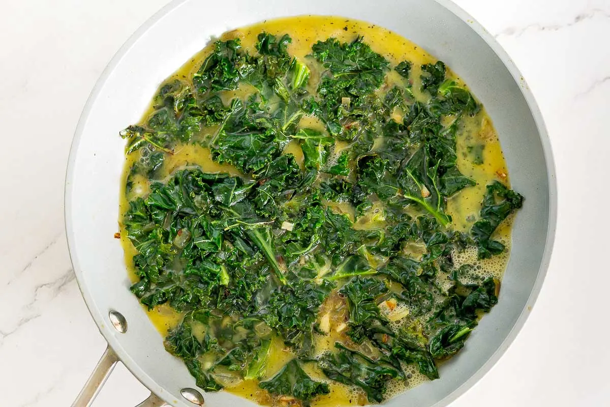 Sauteed kale and onion with scrambled egg in a pan.