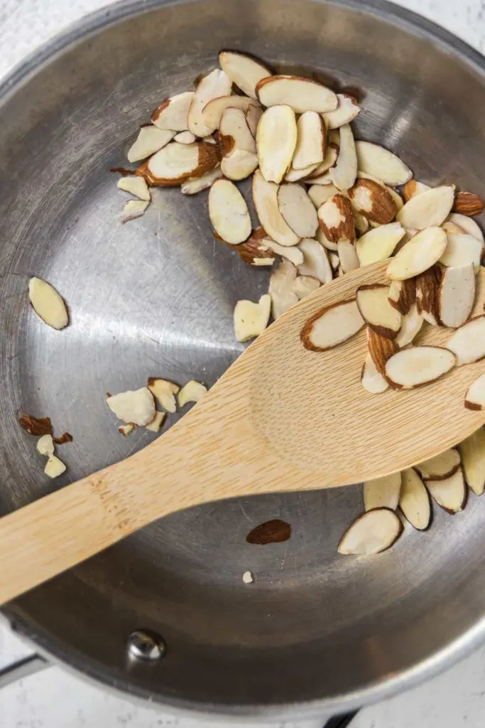Toasting sliced almonds in a pan.