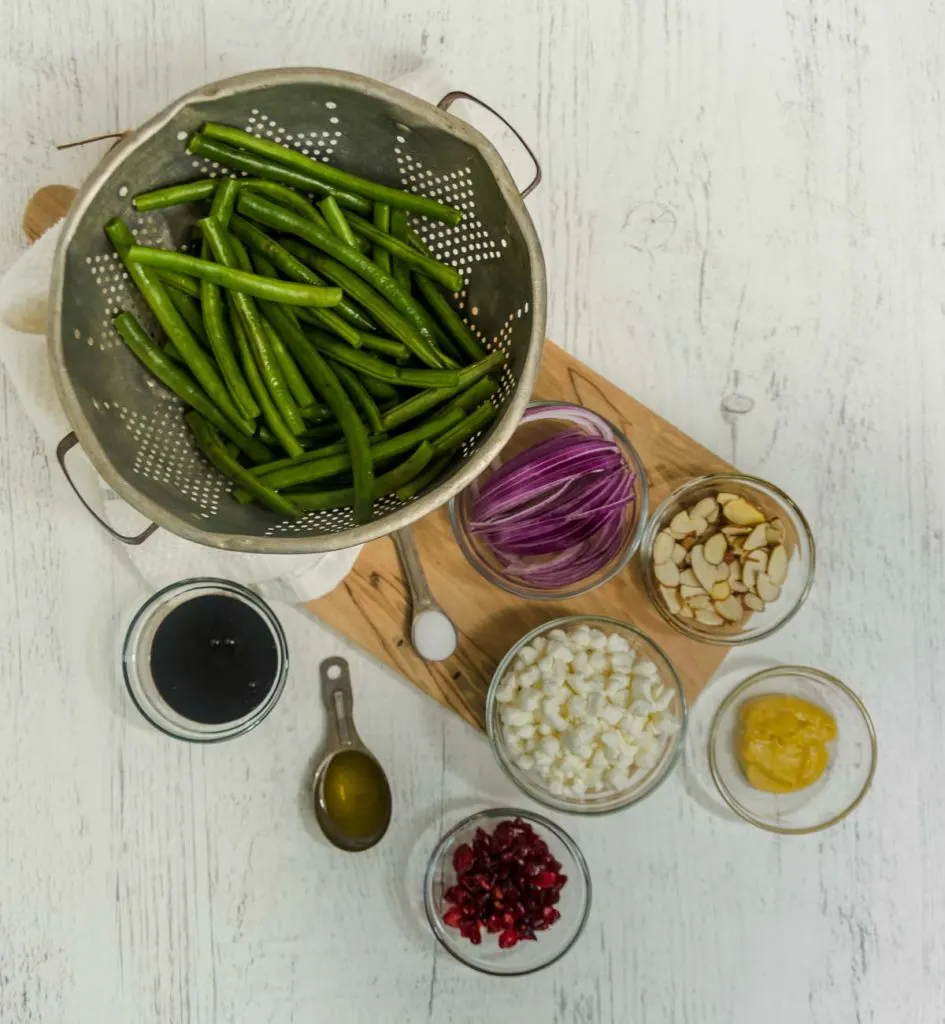 Ingredients to make green bean side dish: Green beans, balsamic glaze, Dijon mustard, red onions, craisins, almonds, and goat cheese.