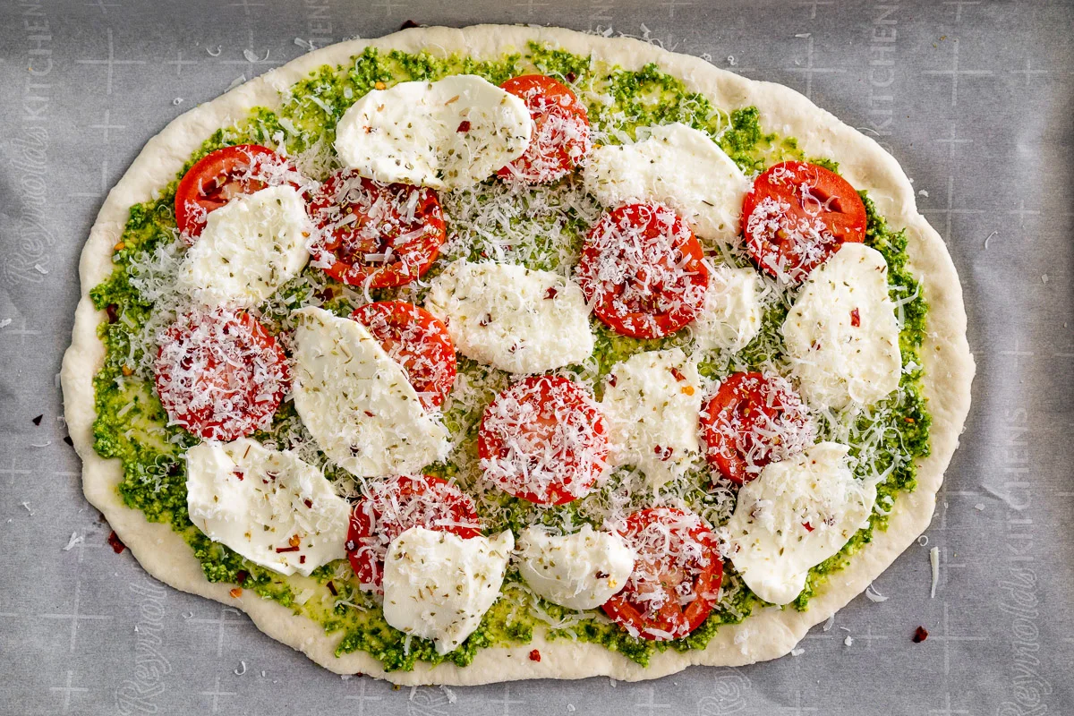pesto pizza toppings on pizza dough