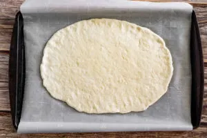pizza dough stretched out on a baking sheet