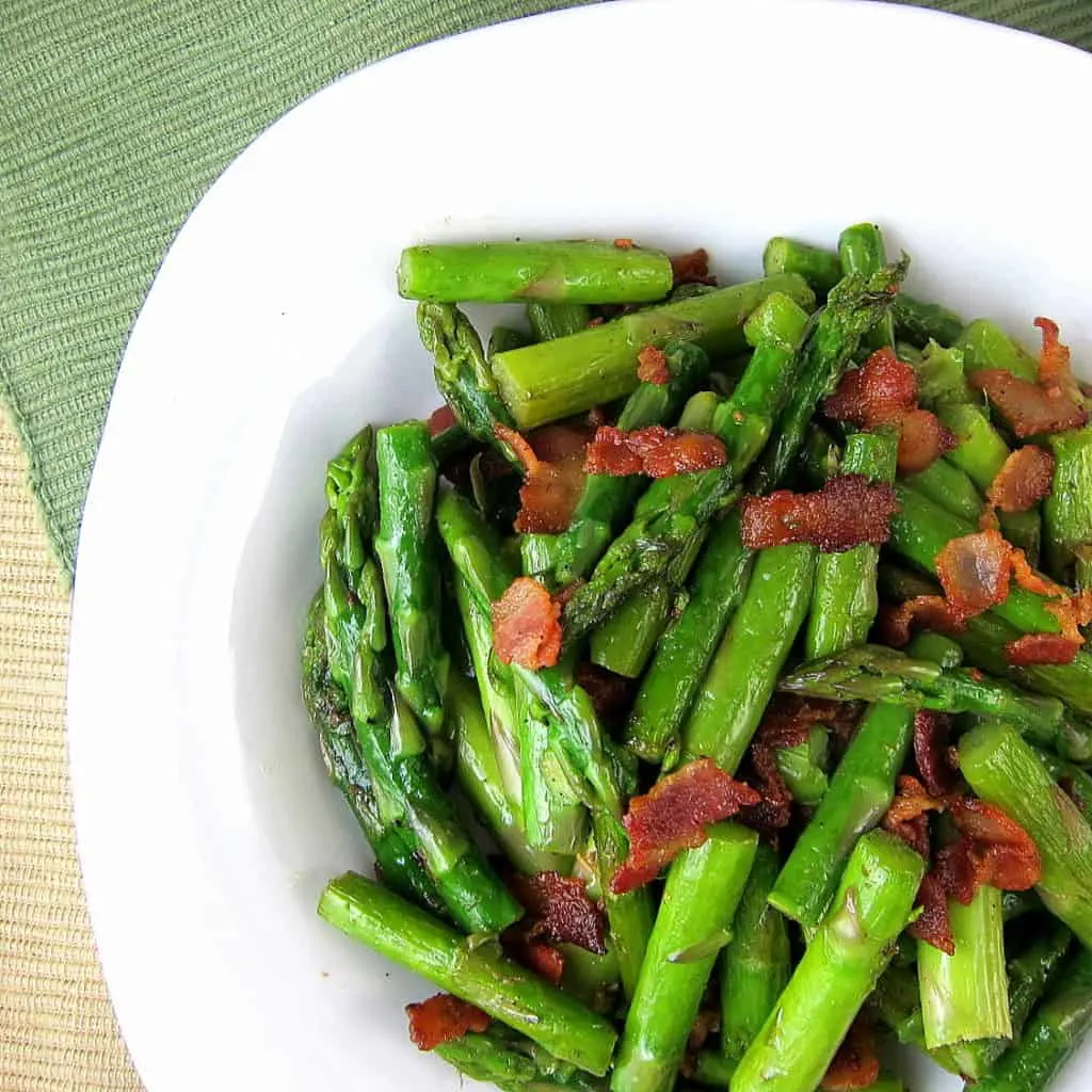 Plate of chopped sauteed asparagus with pieces of bacon