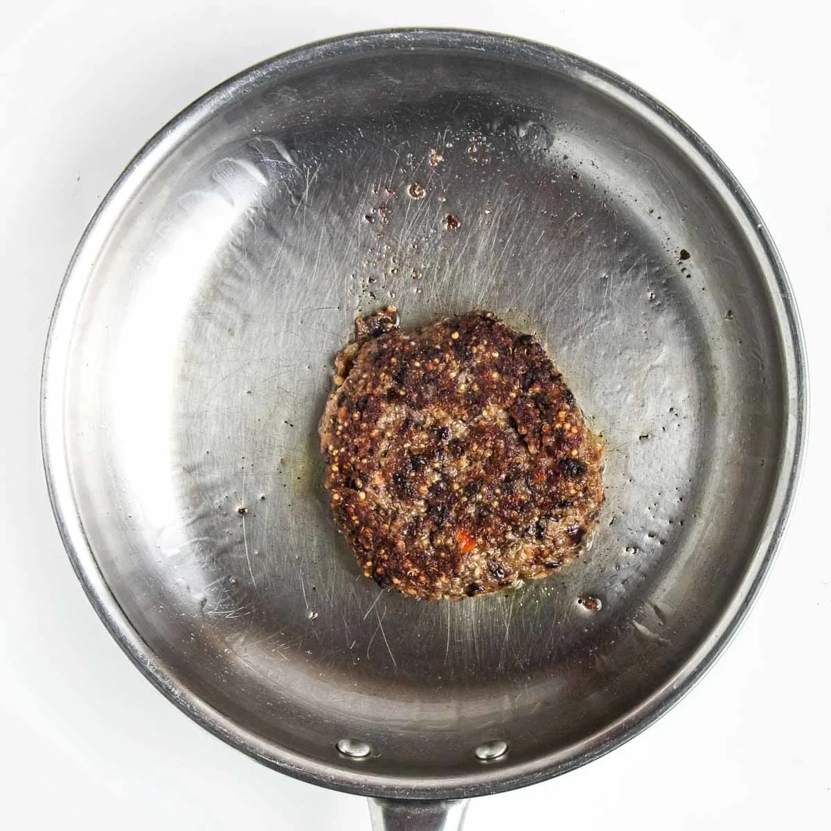 Black bean quinoa burger cooking in a pan