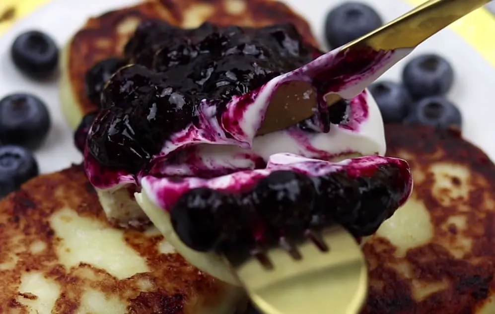 syrniki recipe - russian cheese pancakes with sour cream and blueberry preserves