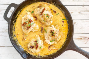creamy sun dried tomato chicken thighs in a skillet