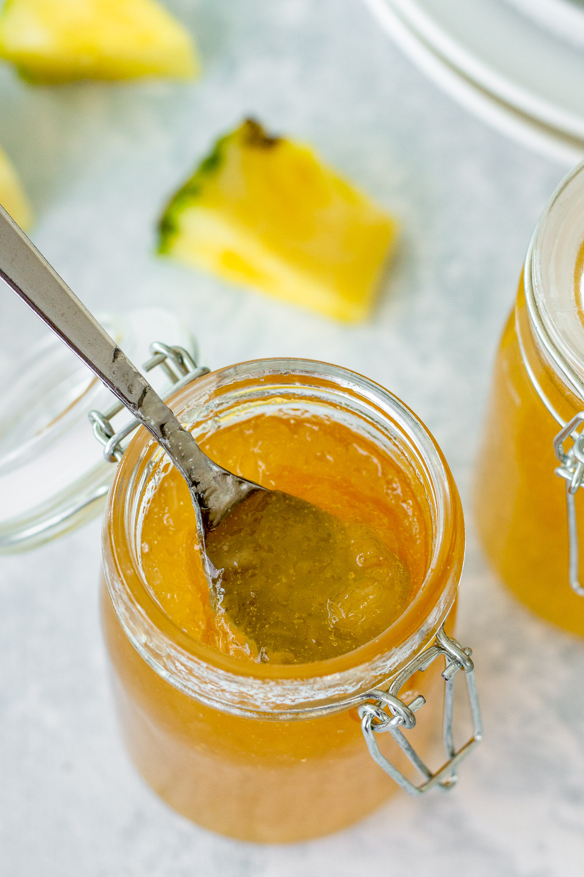 pineapple jam in a glass jar with a wedge of pineapple in the background