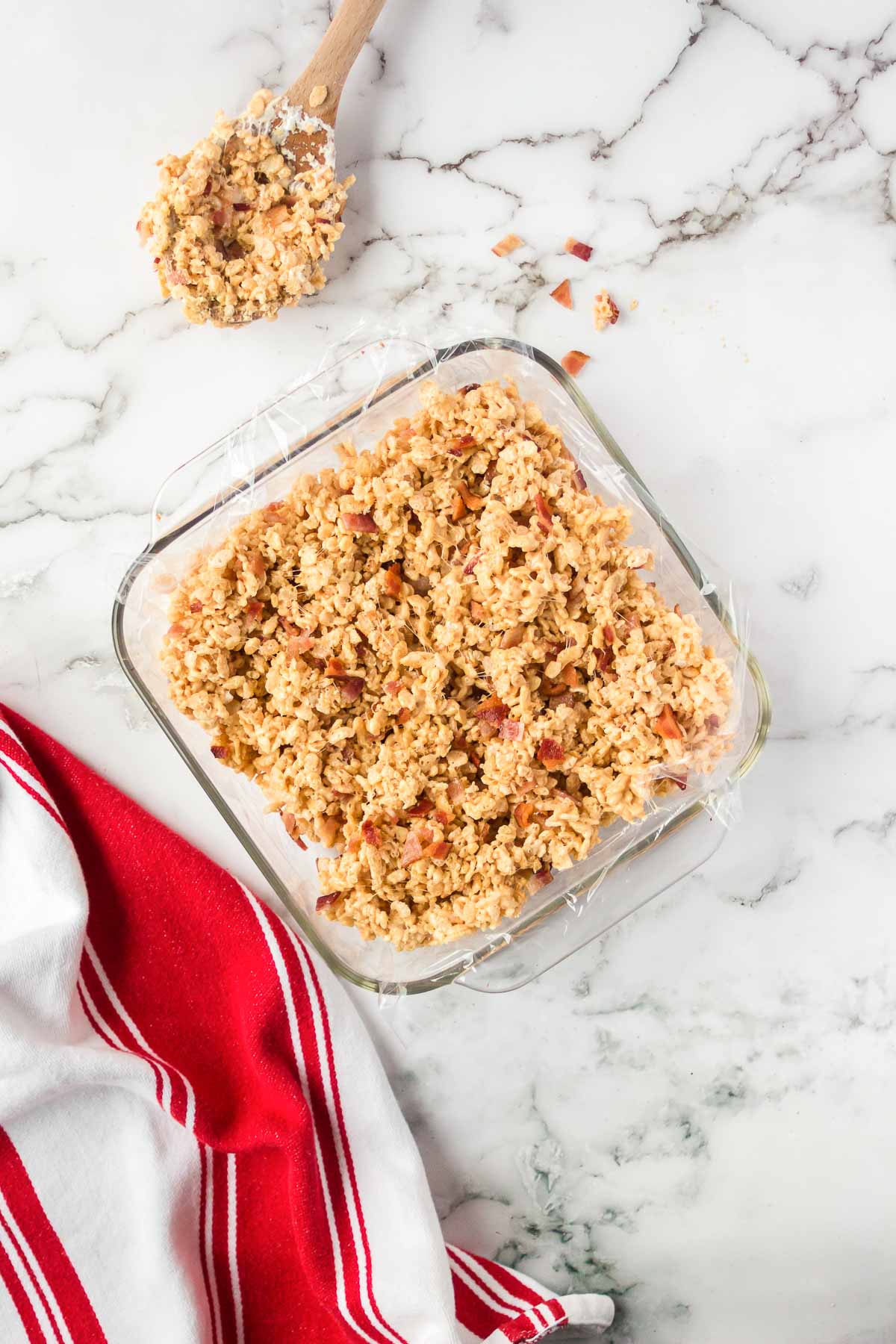 Peanut butter rice krispies treats with bacon bits pressed into a baking pan. 