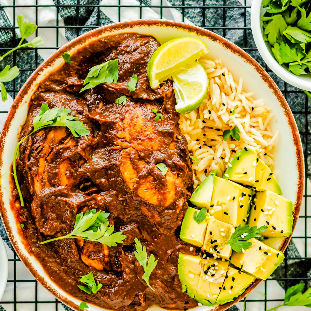 plate of chicken with mole sauce with rice and avocado