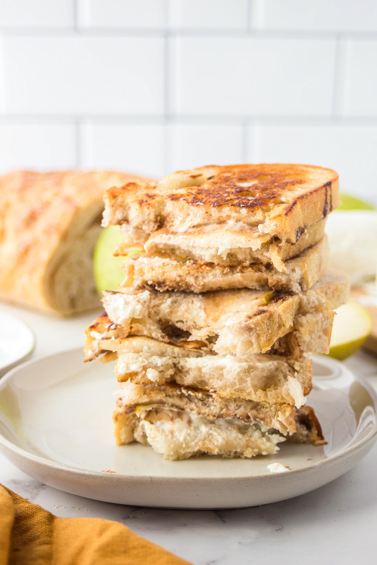 Stacked goat cheese and pear grilled cheese sandwich on a plate.