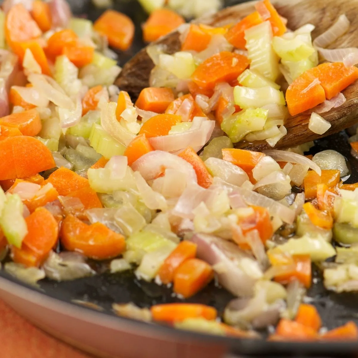 Saut&eacute;ing carrots, onion, and celery in a pan.