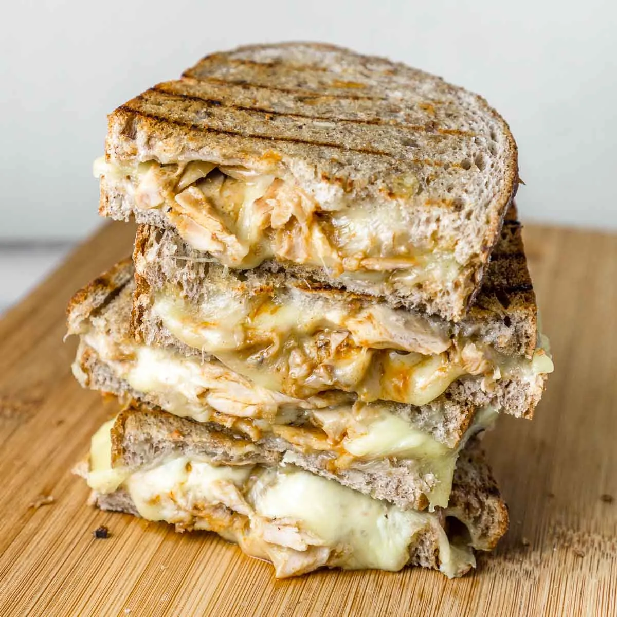 BBQ chicken grilled cheese sandwiches stacked on a cutting boar