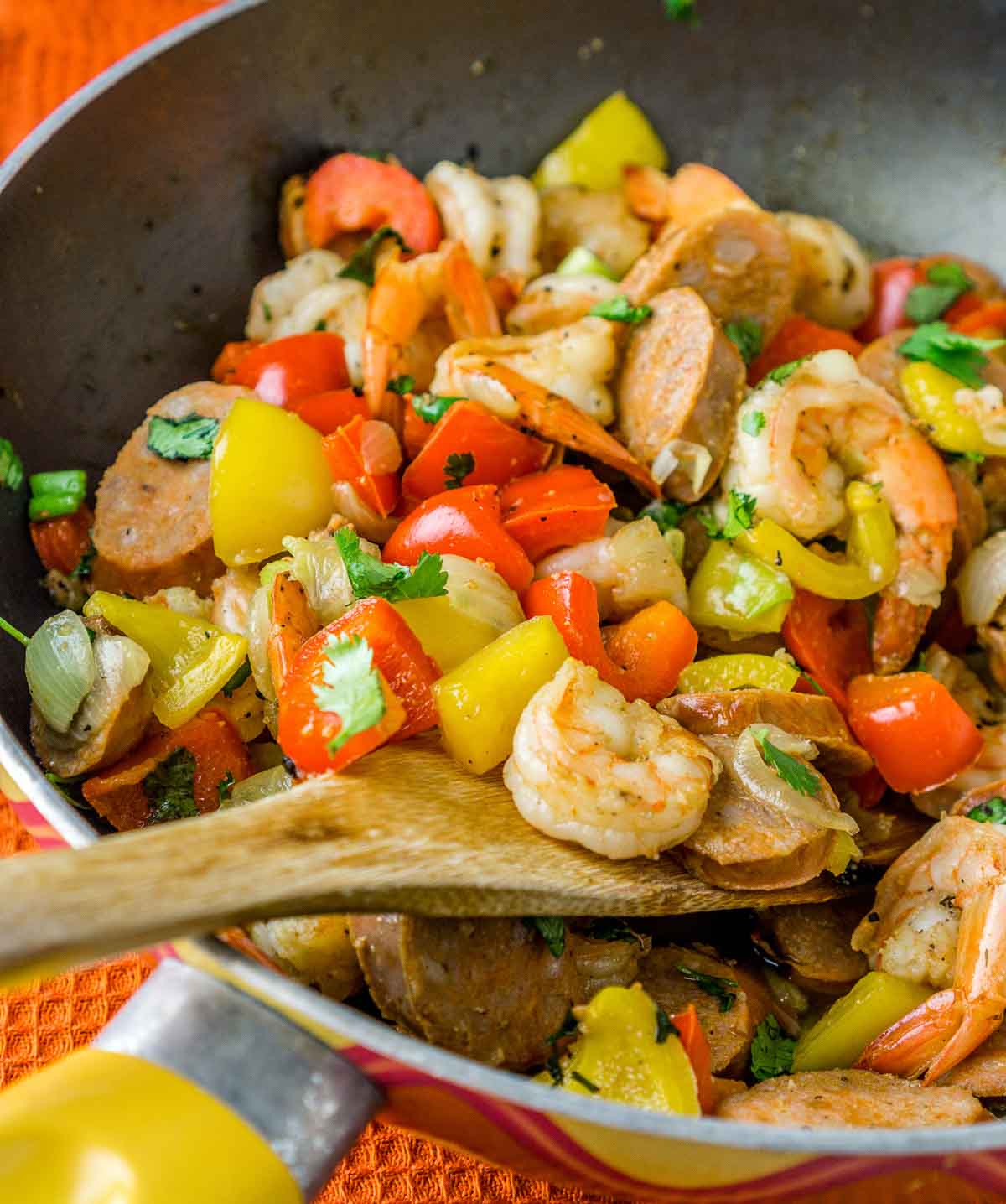 Spatula in a pan with cooked Italian sausage and shrimp