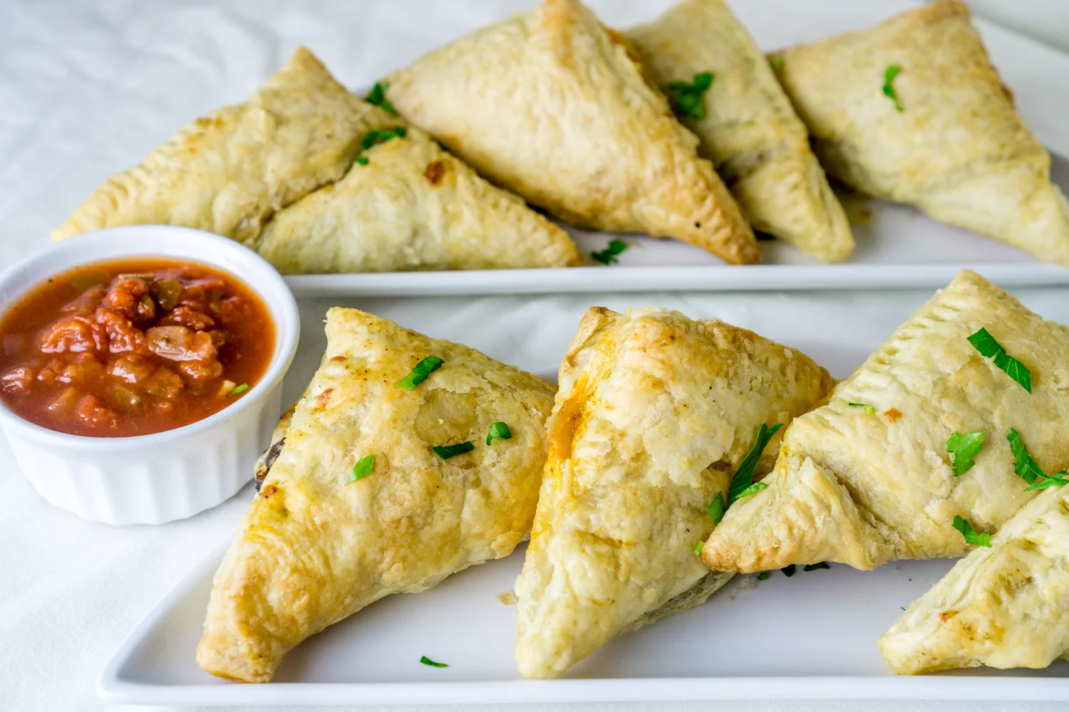 black bean puff pastry triangles with marinara sauce on serving plates