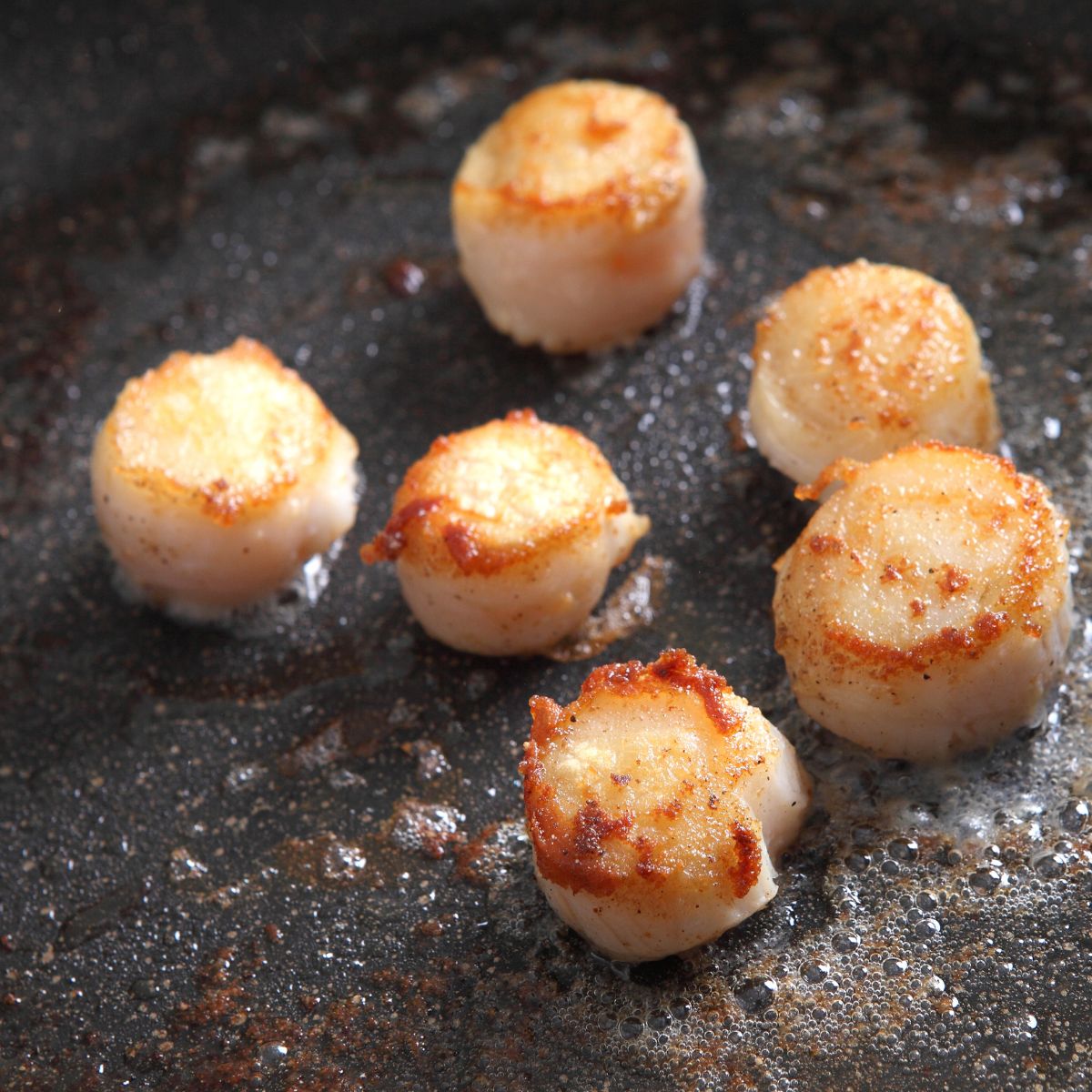 Scallops cooking in butter in a pan