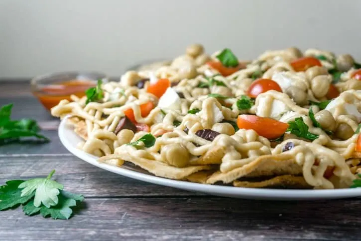 The Mediterranean Pita "Nachos" are a must-try! All the delicious flavors of the Mediterranean in a delicious platter with heart-healthy chickpeas, feta cheese, fresh veggies and herbs, all topped with a yummy hummus sauce. From https://www.babaganosh.org