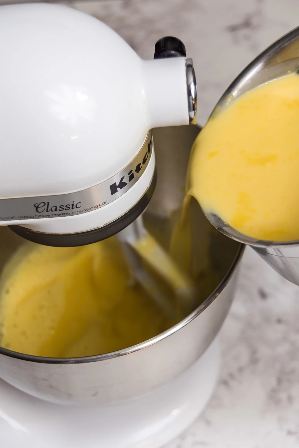 adding eggnog to egg yolks in a mixer