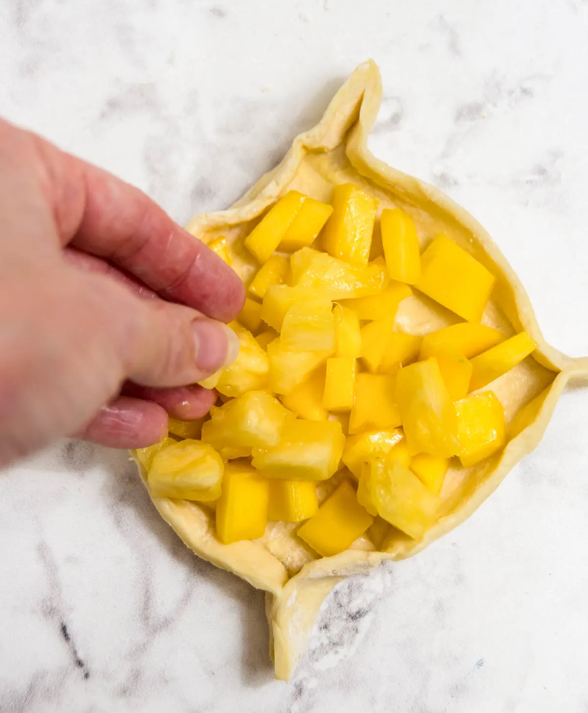 Adding pineapple pieces to puff pastry