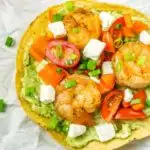 Overhead image of shrimp tostada with peppers, tomatoes, avocado