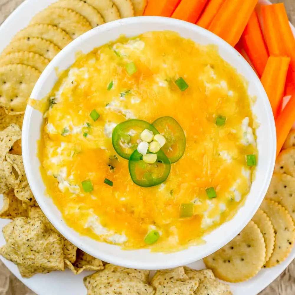 bowl of no-bake cheesy corn dip with cream cheese, topped with jalapeno slices