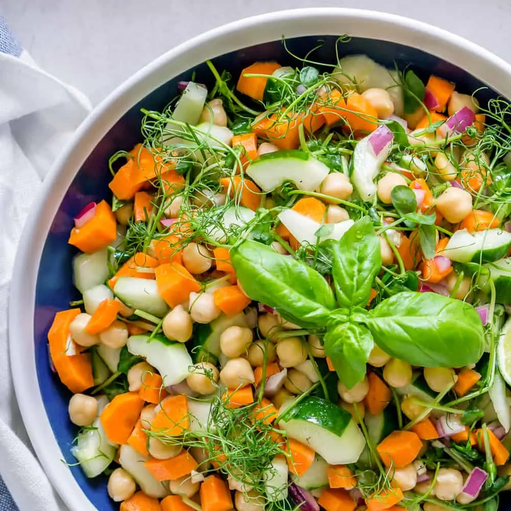 Chickpea and Pea Shoot Salad in a bowl garnished with basil.