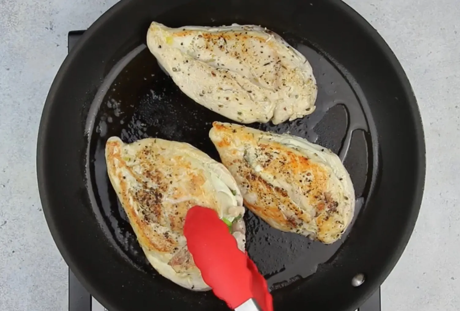 image of stuffed chicken breast cooking in skillet