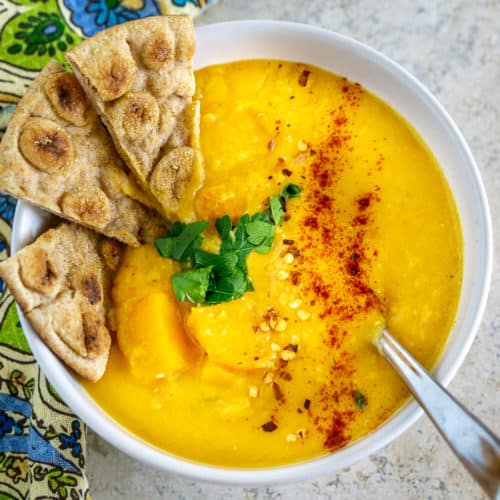 bowl of lentil butternut squash soup with garlic pita wedges