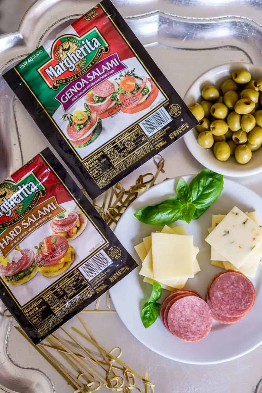 ingredients to make an easy salami appetizer: salami, olive, cheese on a tray