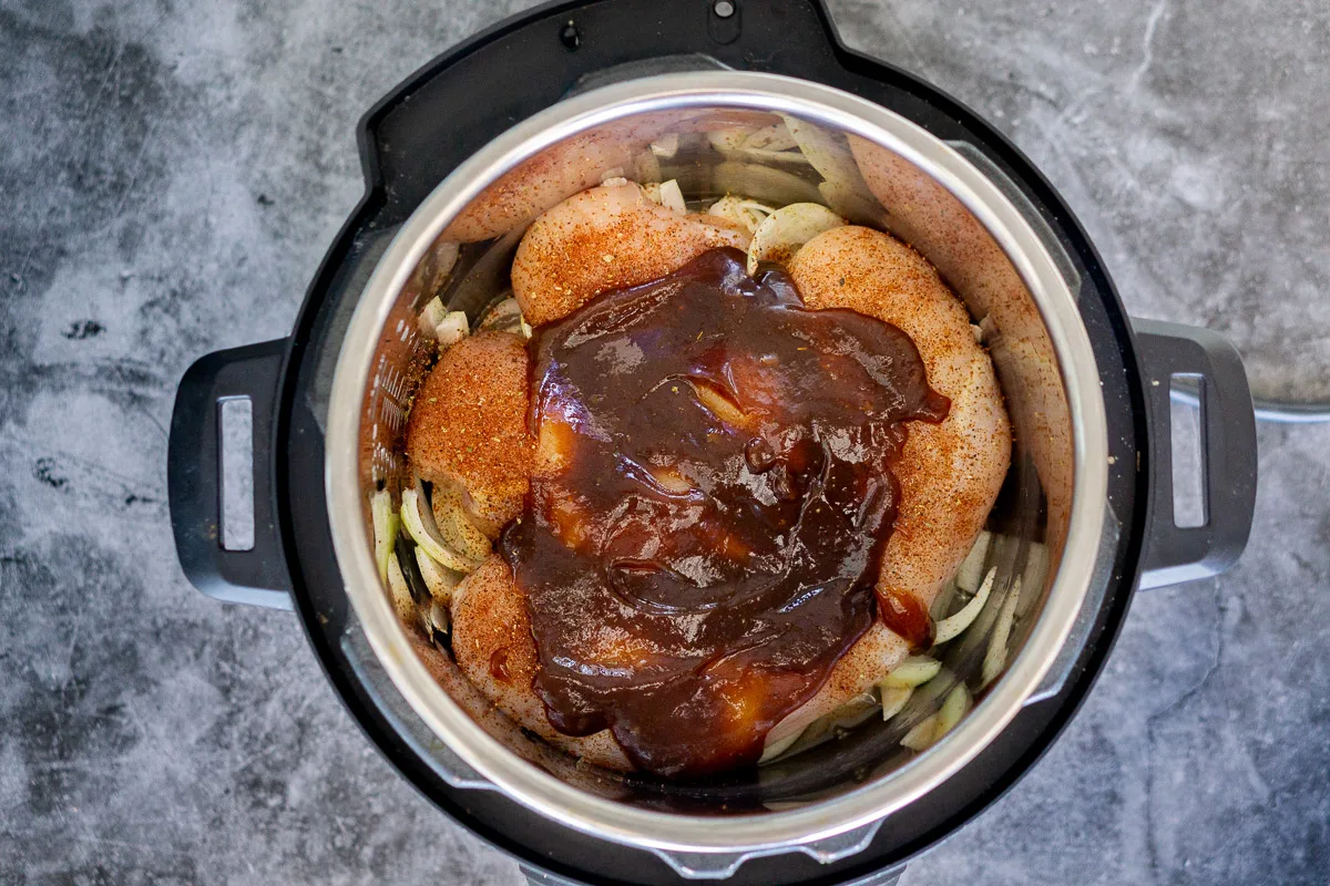 Instant pot with chicken, BBQ sauce, and onions in it