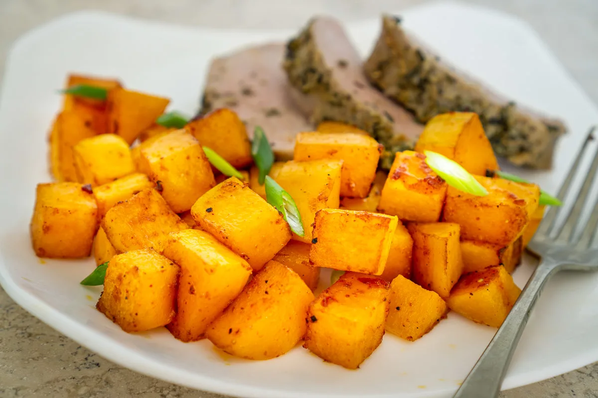 gochujang roasted butternut squash on a plate with pork chops
