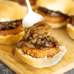 putting caramelized onions on a sausage slider