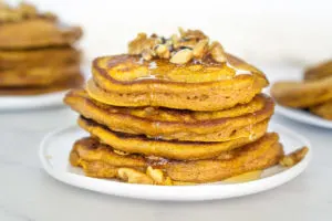 stack of pumpkin pancakes with chopped walnut pancake topping