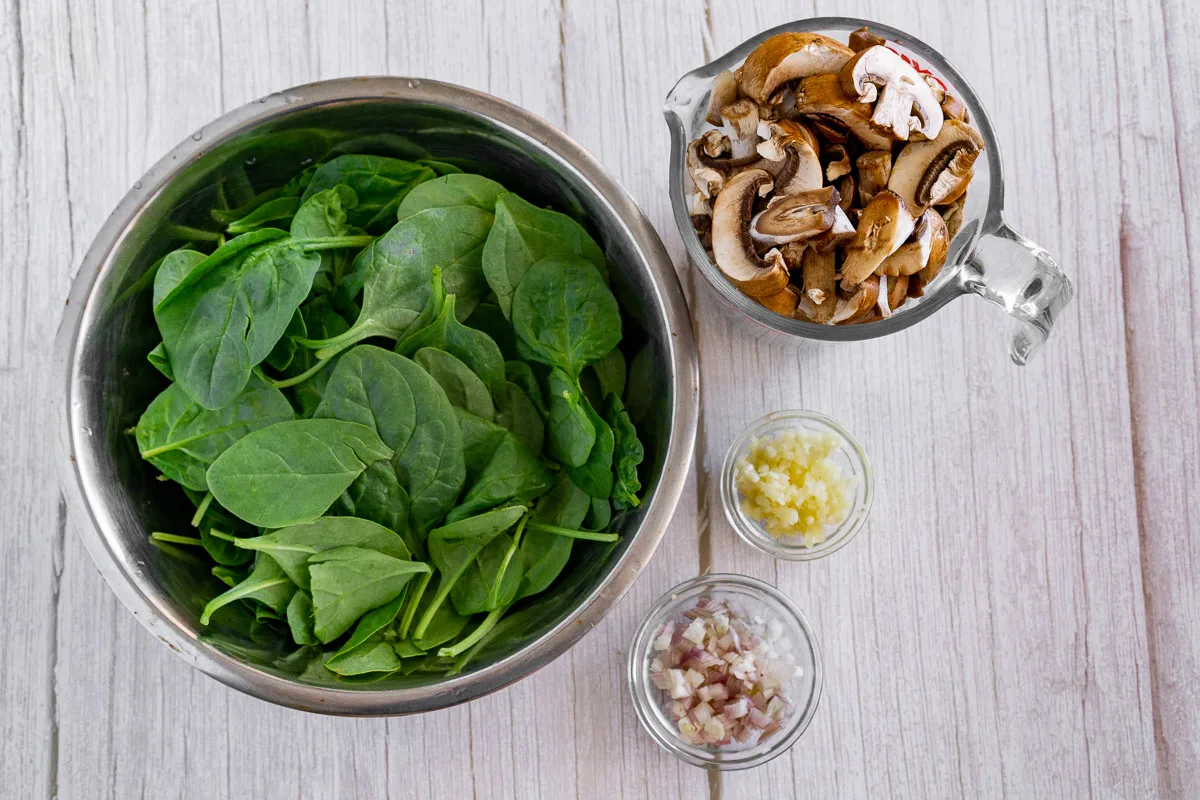 picture of ingredients for one-pot pasta with mushrooms: sliced mushrooms, baby spinach, garlic, shallots