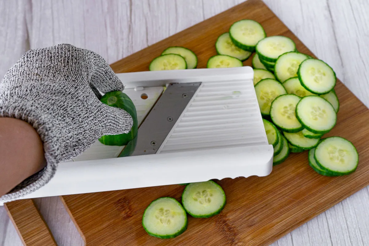 slicing cucumbers for salad on a mandoline
