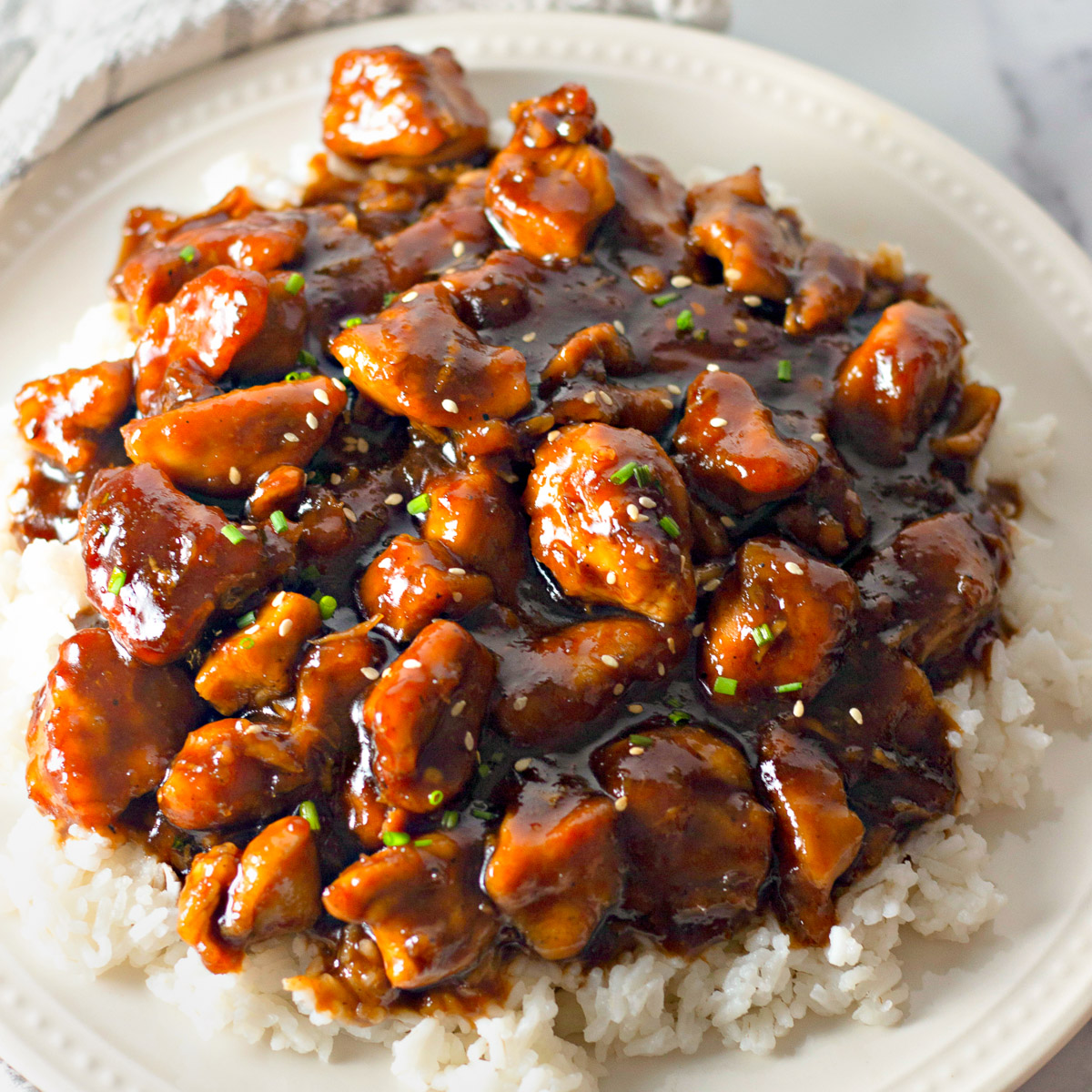 bourbon chicken over a bed of rice on a plate