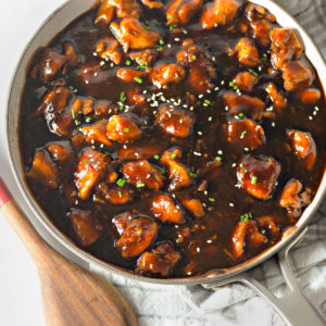 pan of bourbon chicken with a bowl of rice on the side