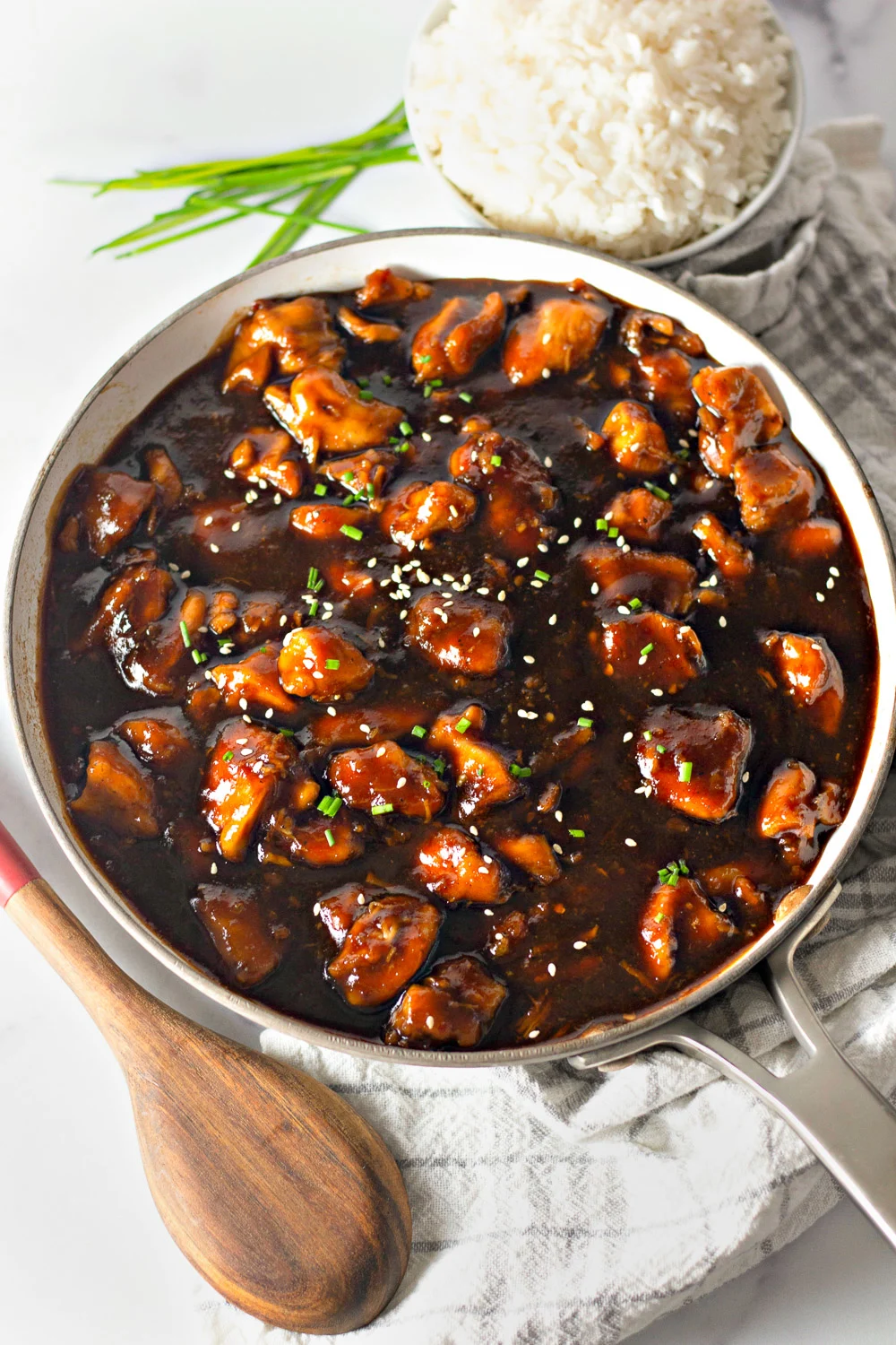 pan of bourbon chicken with a bowl of rice on the side