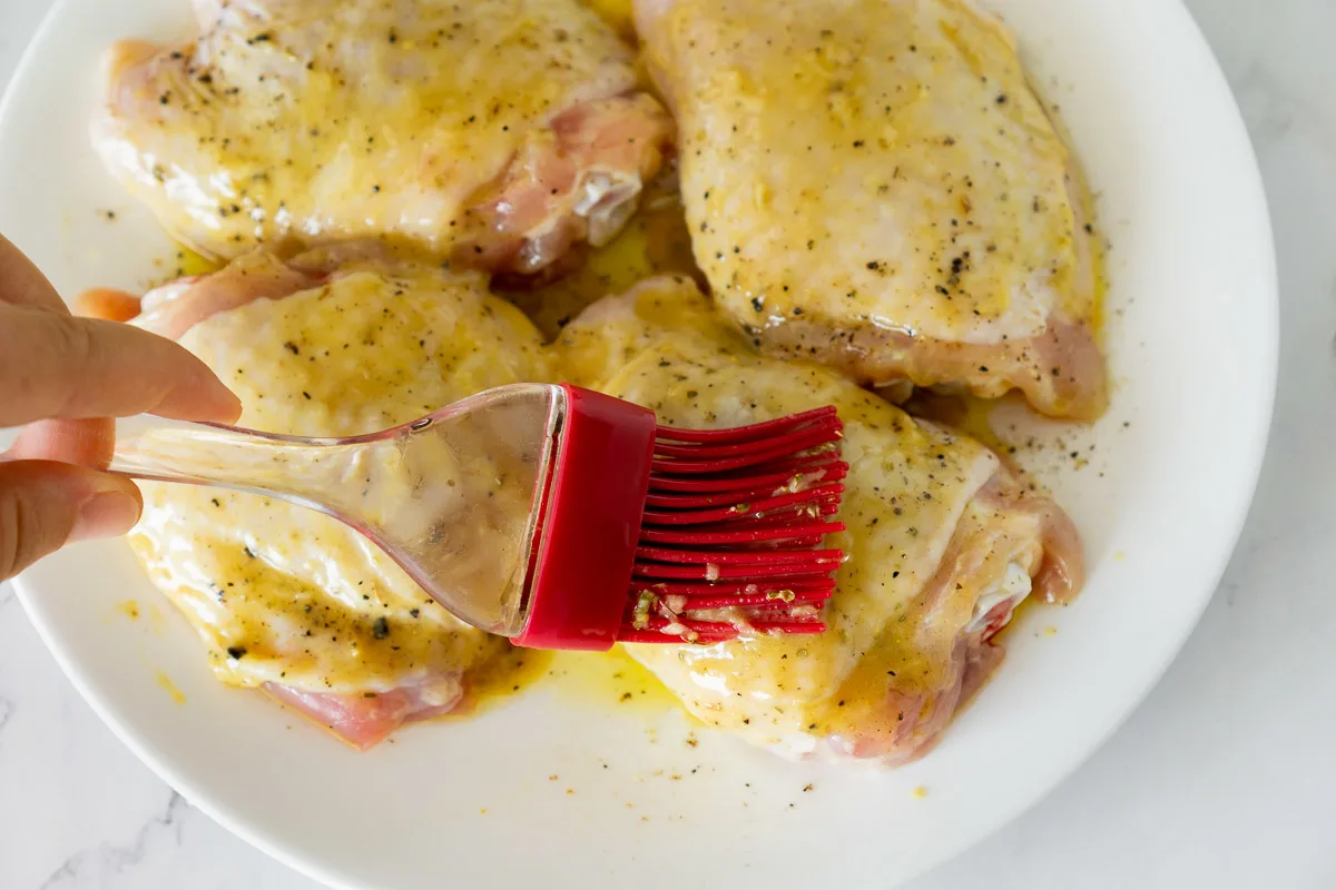 brushing honey mustard sauce onto chicken thighs