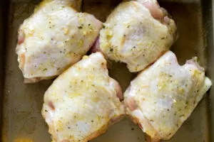 chicken thighs brushed with honey mustard sauce on a baking pan ready to be cooked